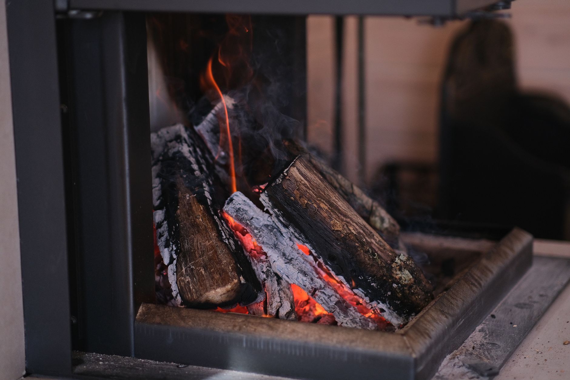 Firewood burning in a modern indoor fireplace — smoke backdraft causes and solutions