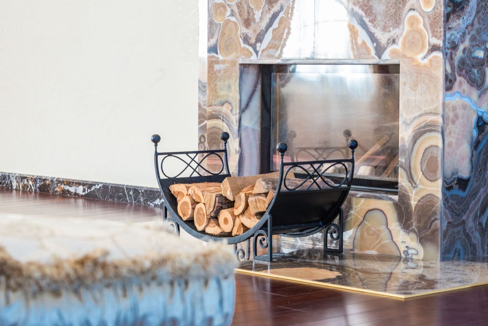 Stone fireplace surround with a wrought-iron log holder on the hearth